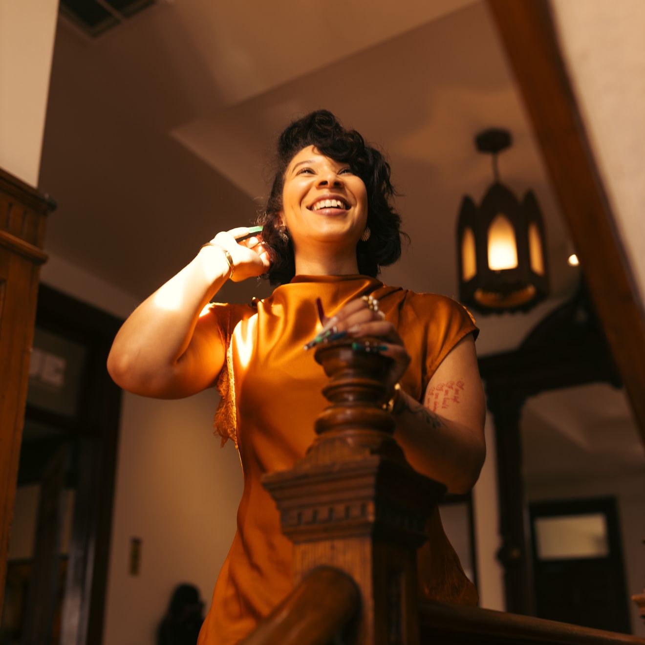 Woman in an orange dress standing in a warmly lit room with wooden decor. | B. Marie Accessories, Shannon Johnson, DMV