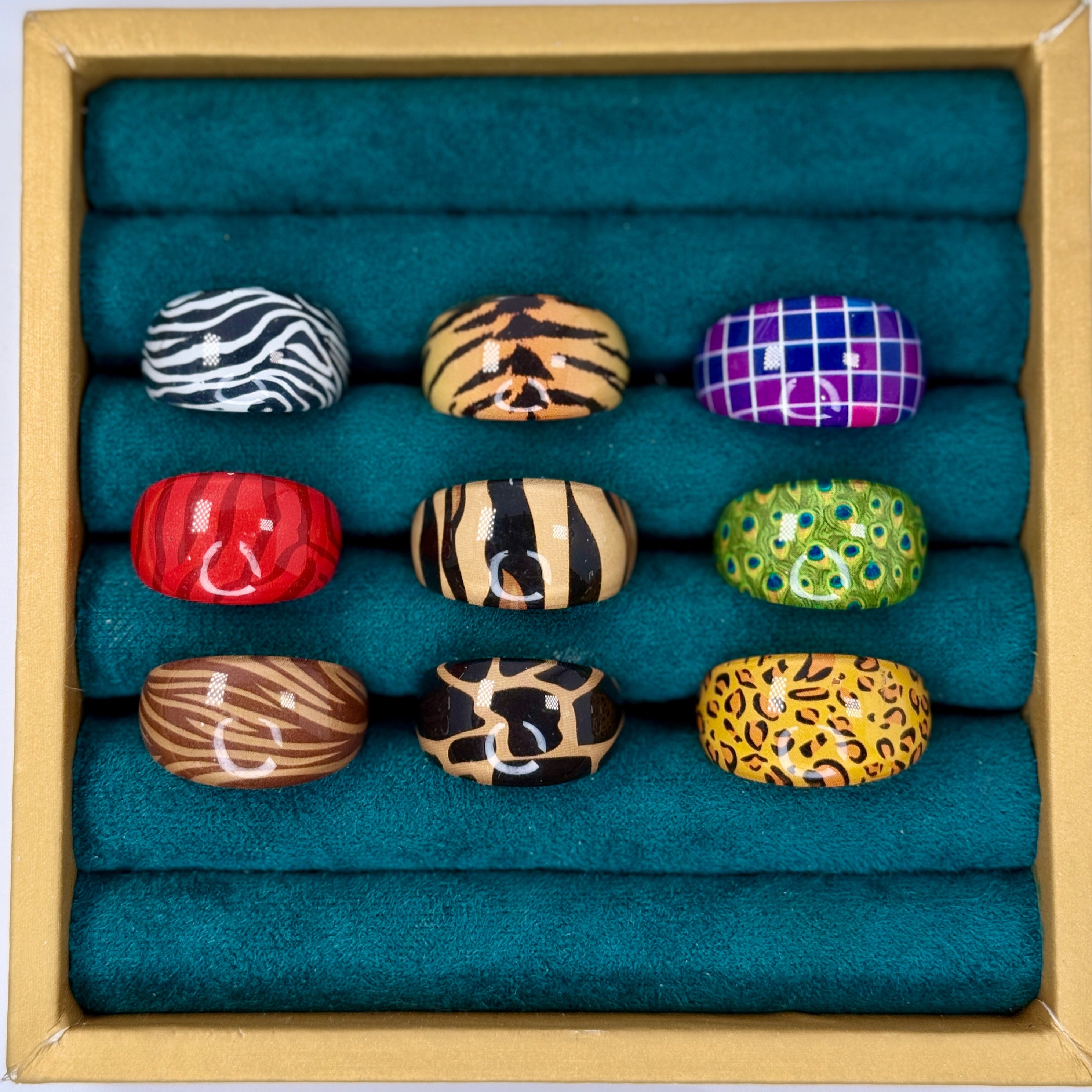Set of colorful rings in a wooden box with teal cushioning